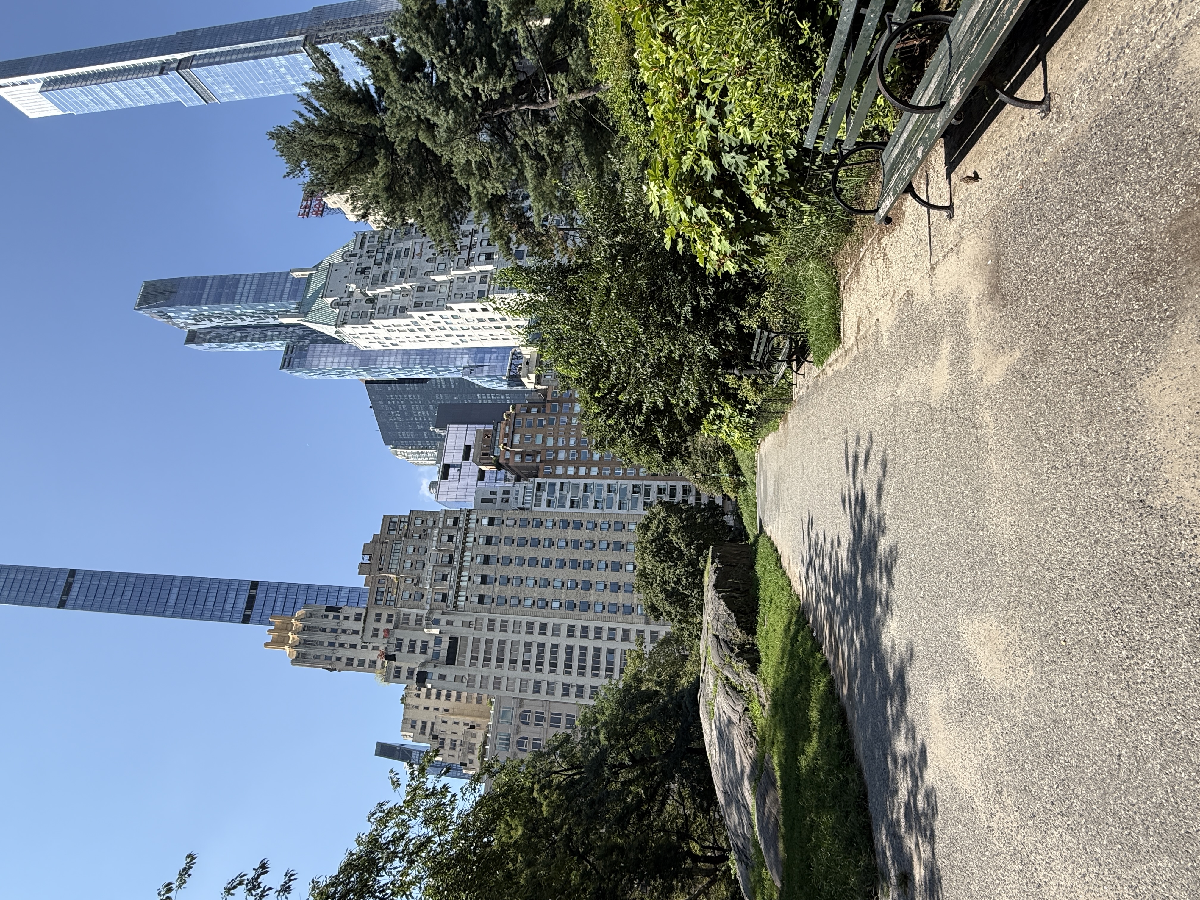A wooded trail in Central Park leading toward Manhattan high-rise buildings