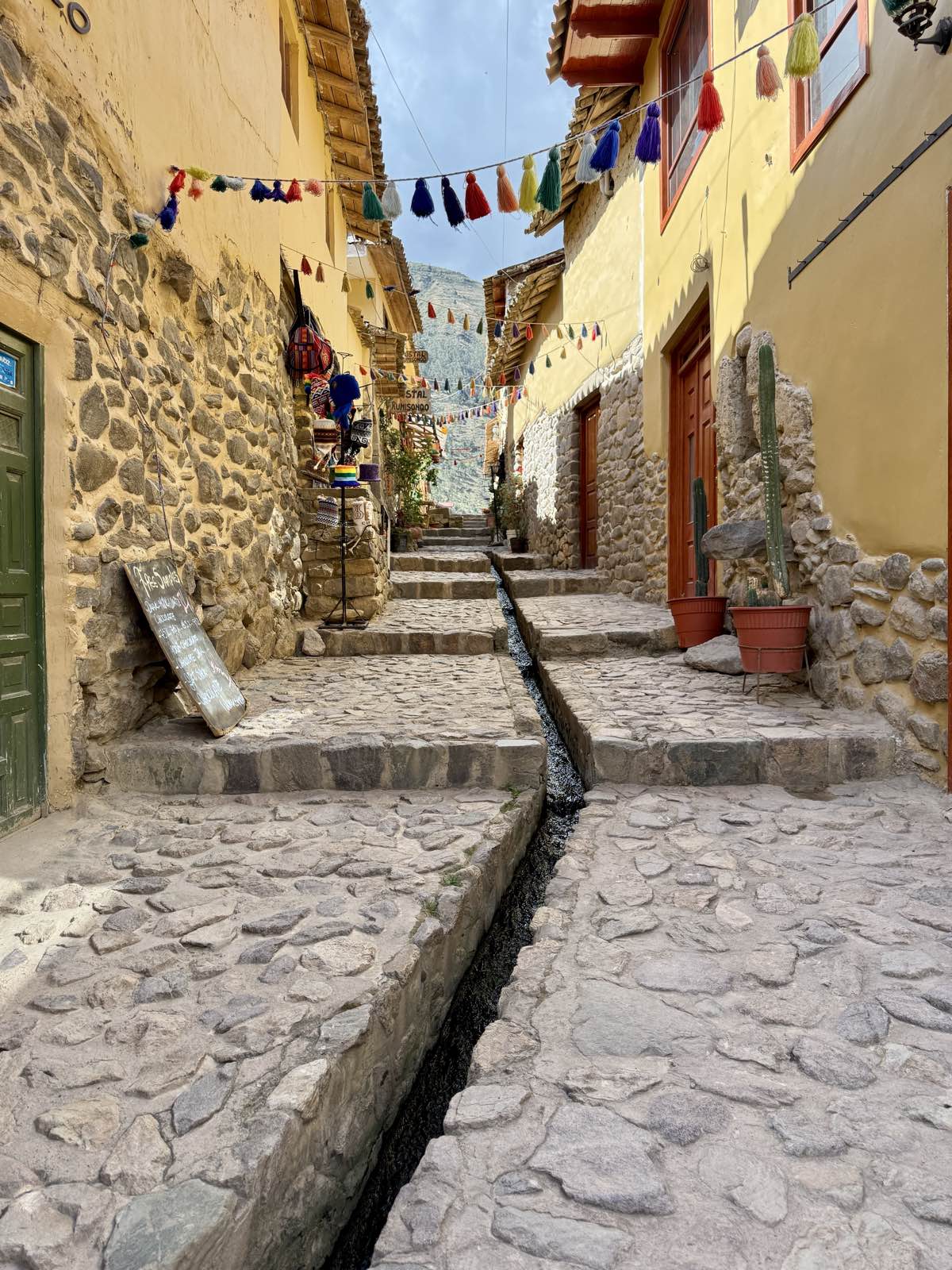 Cobblestone street with a stone water channel and colorful tassels strung overhead