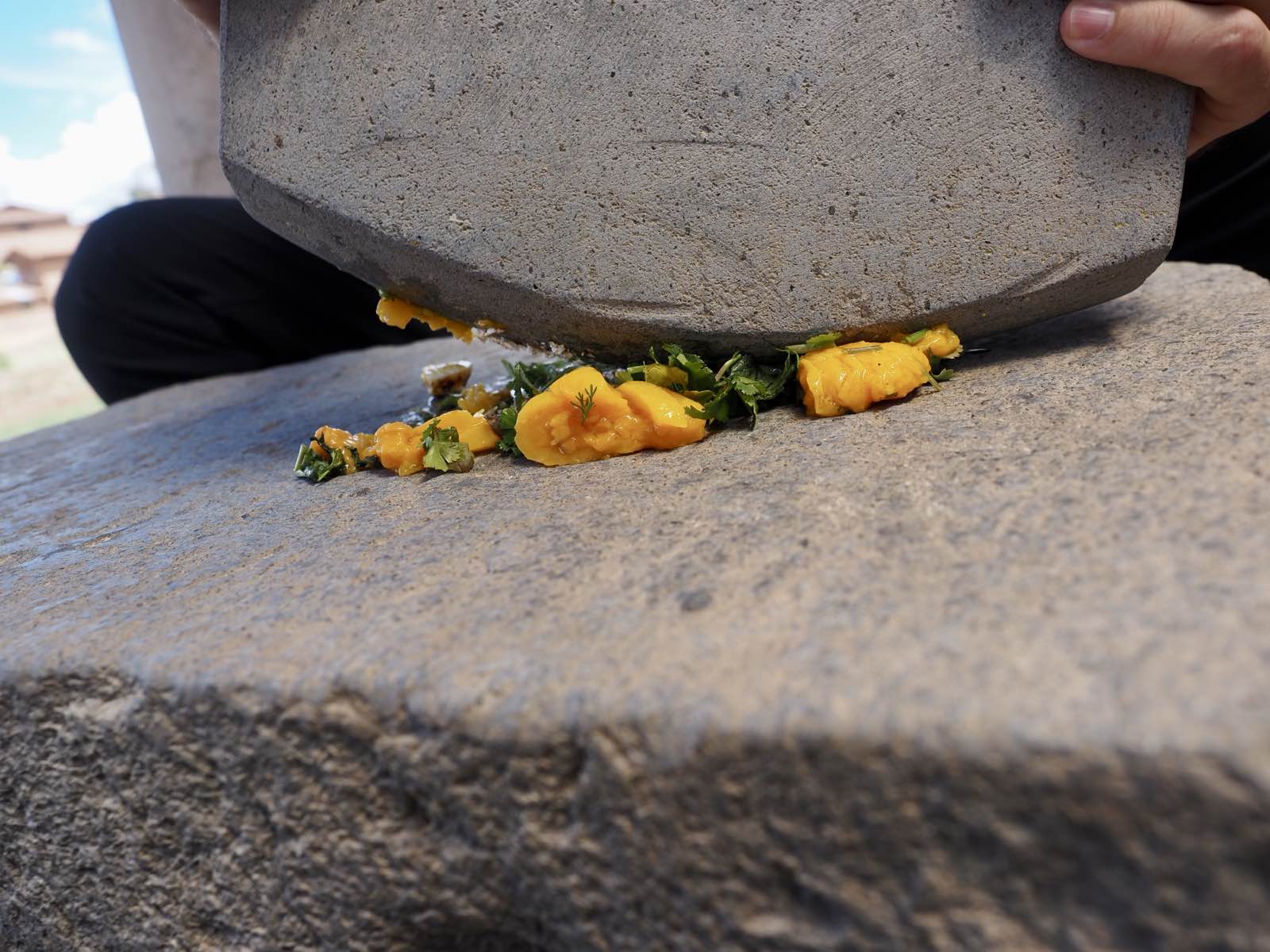 A stone rocking over peppers and herbs to make salsa