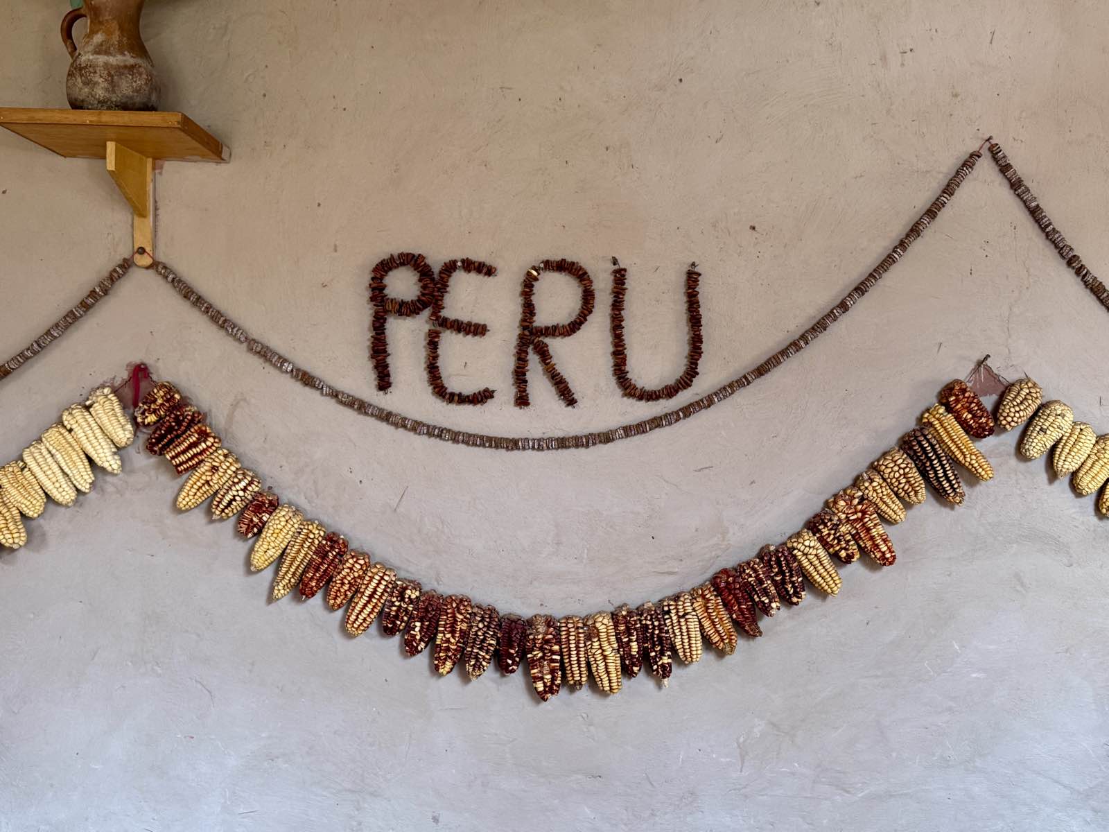 The word PERU spelled out in dried corn kernels above a garland of Andean corn